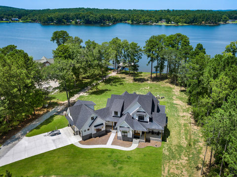 White House with hardie siding, stone veneer, and shingle roof at the lake