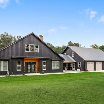 Exterior view of luxury house with black metal siding and metal roof, landscaping, luxury home with four car garage