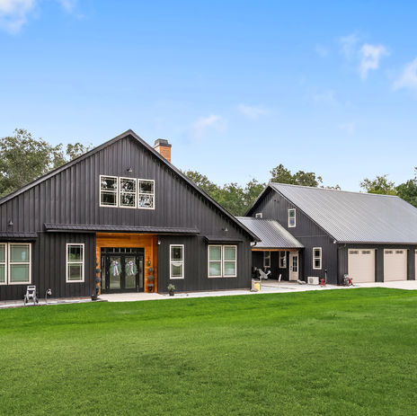 Luxury custom home with black metal siding and metal roof, wood accents