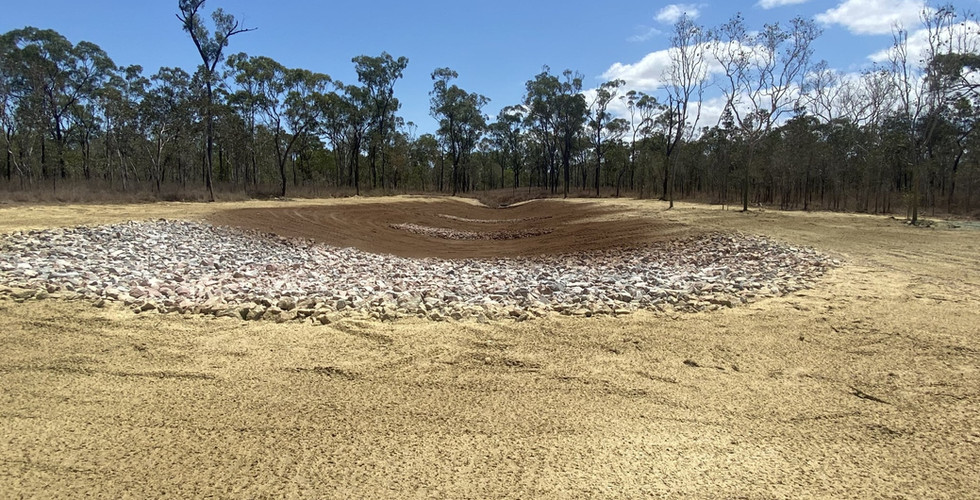 A cleared area of land, with a rock wall built and new soil behind