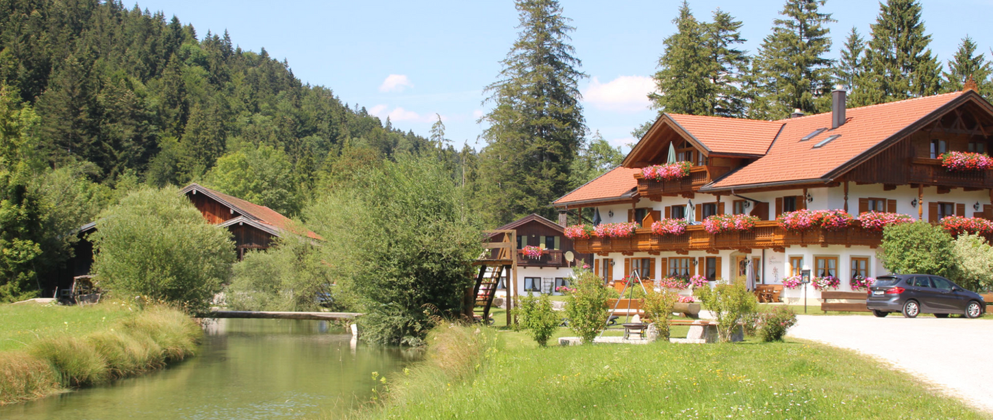 Traditionelles Gebäude mit Blumen am Bach und Wald