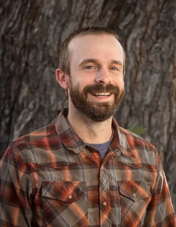 man standing in front of a tree smiling