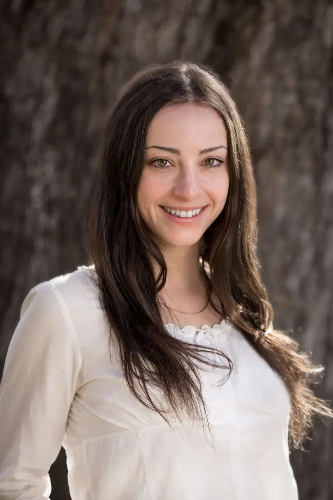 woman stands smiling in front of tree