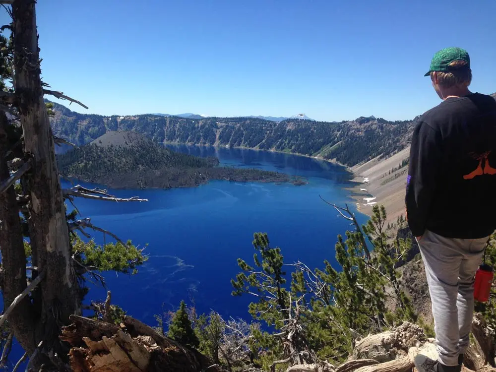 man stands in front of crater lake in Oregon