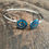 Thumbnail: Silver bangle bracelet with blue opal spiral design on wooden surface.