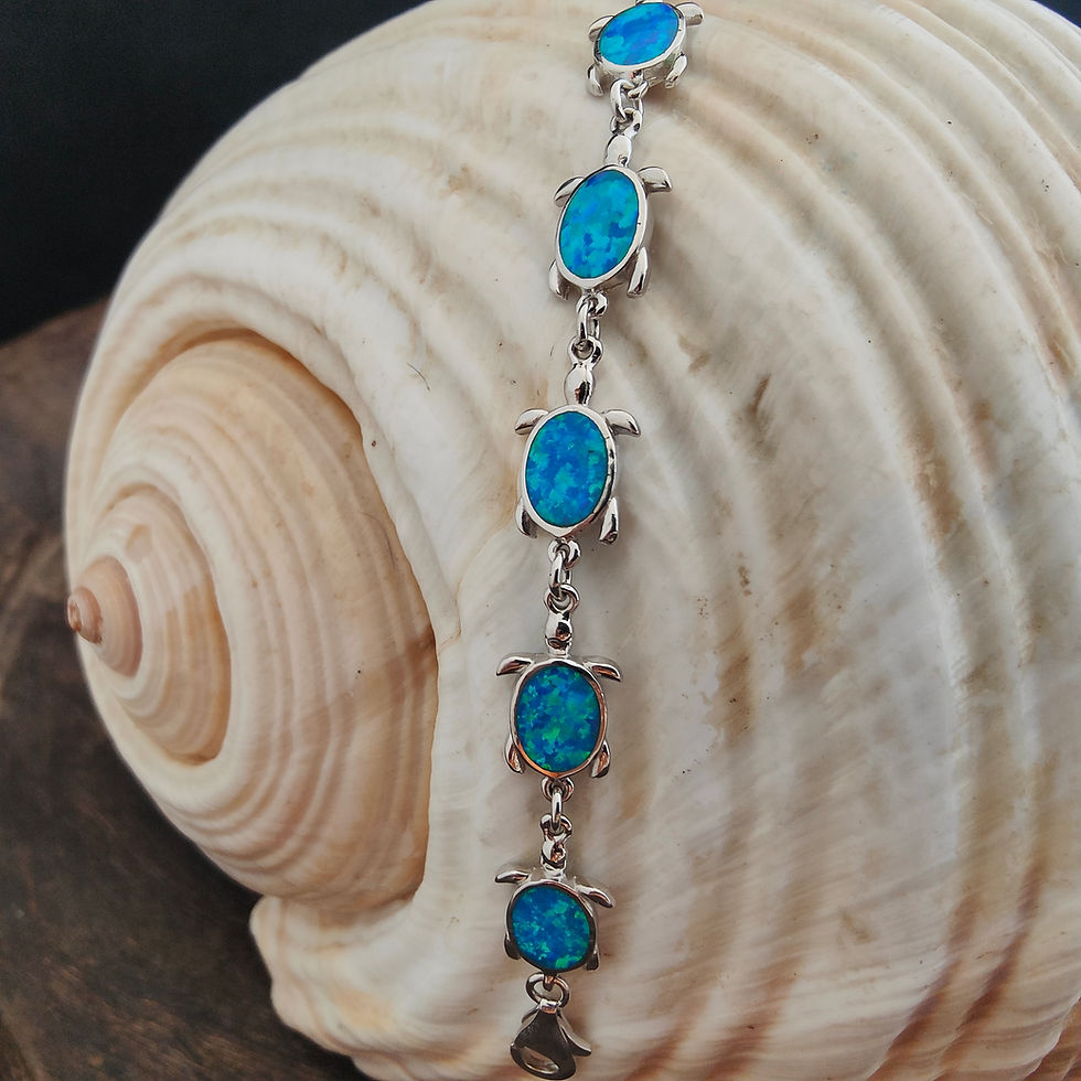 Silver bracelet with blue turtle charms on a sea shell background