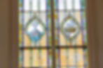 Stained glass panels depicting a cross on a rock above water and a cross with a crown, representing Christ’s steadfastness