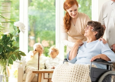 Caregiver supporting senior woman in a wheelchair.