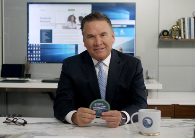 Man in a suit holding a small round object in an office.