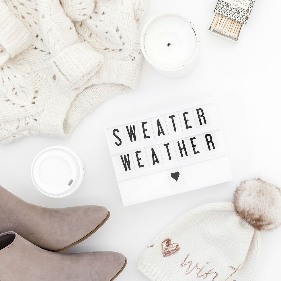 Flatlay of fall essentials on a white background, including a chunky sweater, boots, a to-go coffee cup, and a word board that says “Sweater Weather,” styled for a September reset mood.