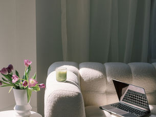 Bride planning for a wedding expo at home with laptop, matcha, and fresh tulips on the table.
