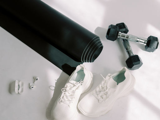 Flat lay of a yoga mat, white sneakers, a laptop, small black dumbbells, and AirPods — essentials for a wedding morning calm routine.