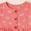 Thumbnail: Close-up of pink cotton top with white butterfly and heart print, round neckline, and wooden buttons