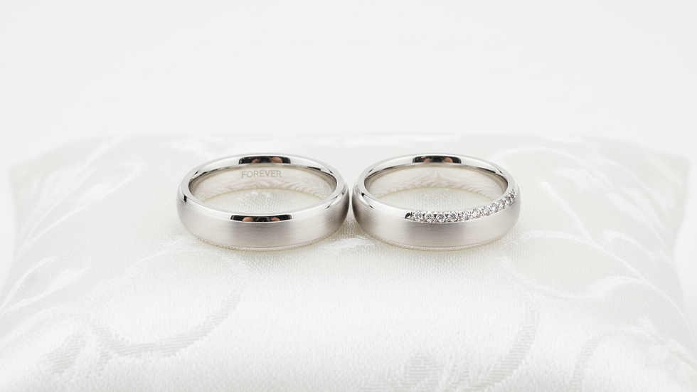 Close-up view of a pair of silver wedding rings on a white cushion