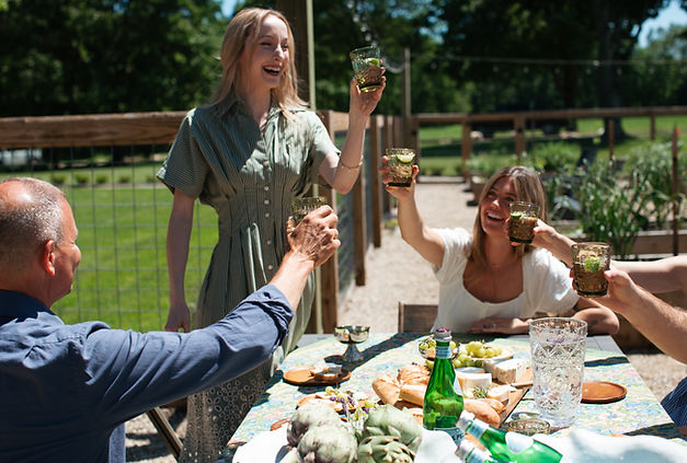A girl in green giving a toast to a group outside