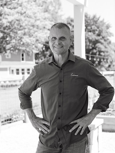 black and white photo of man standing on porch