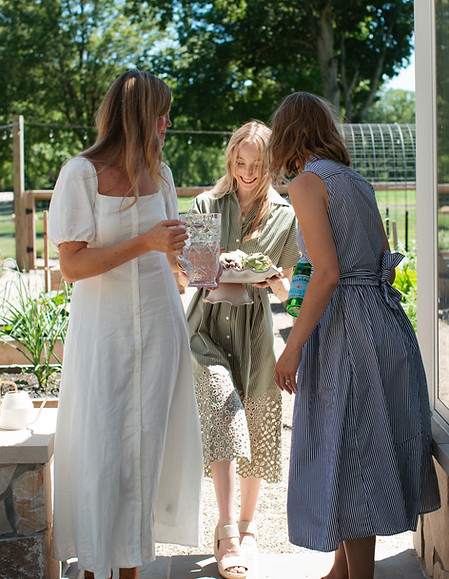 three women in dresses walking onto porch