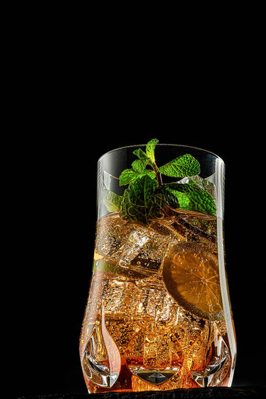 Hochwertige Food- und Getränkefotografie eines eleganten Cocktails mit Eiswürfeln, Zitronenscheibe und frischer Minze vor tiefschwarzem Hintergrund. Die präzise Lichtsetzung betont Kohlensäure, Transparenz, Textur und Glasreflexionen und erzeugt eine luxuriöse, bar-ähnliche Atmosphäre. Ideal für Bars, Spirituosenmarken, Getränkekarten, Social Media Kampagnen, Werbung und Branding im Beverage-Bereich. Optimiert für Suchbegriffe wie Cocktail Fotografie, Drink Fotografie, Beverage Photography, Produktfotografie Getränke, Bar Fotografie, Werbefotografie Spirituosen und hochwertige Content-Produktion für Markenaufbau und Reichweite.