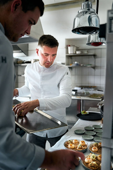 Authentische Servicebegleitung in einer Restaurantküche – Köche richten während des laufenden Services mehrere Gerichte an
