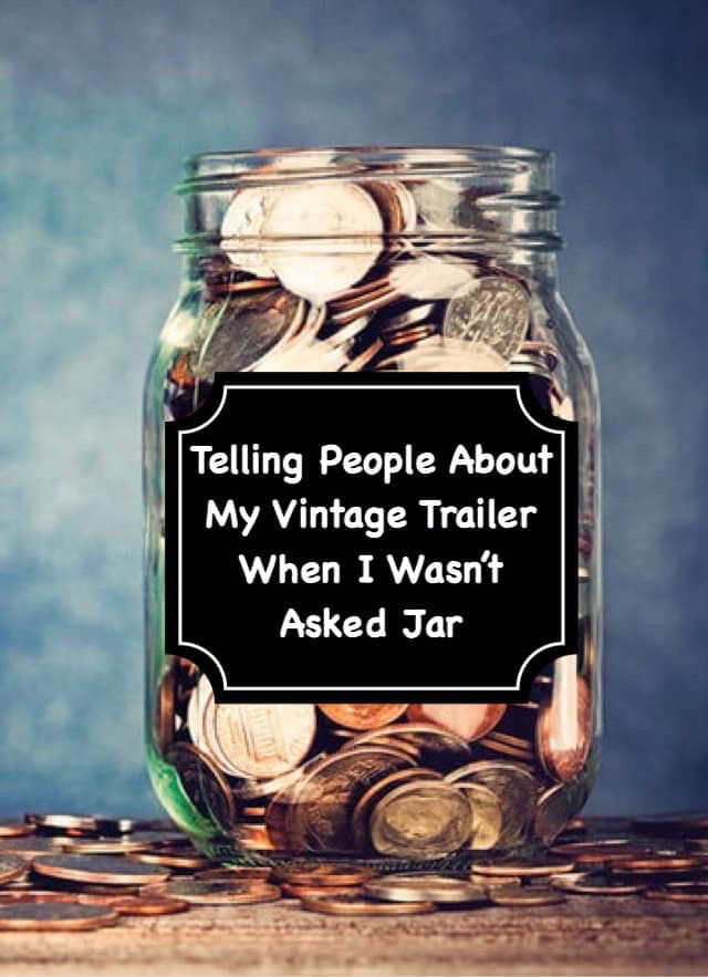 A glass jar filled with coins labeled "Telling People About My Vintage Trailer When I Wasn’t Asked Jar" on a wooden surface, blue background.