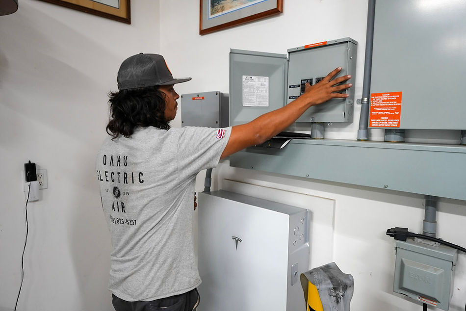 Electrician from Oahu Electric and Air diagnosing electrical issues inside a residential home.