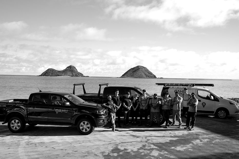 Oahu Electric & Air team standing by work trucks on the Oahu shoreline