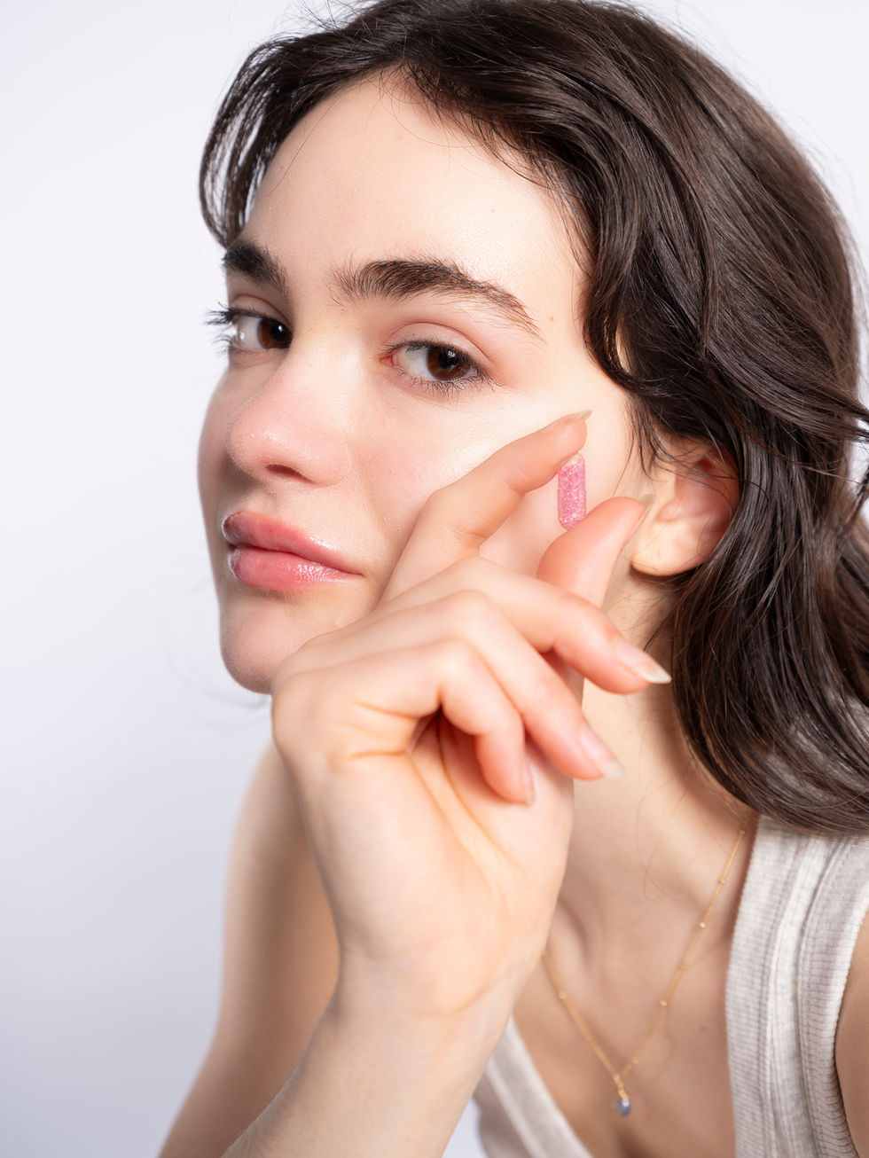 Luxurious beauty close-up showing a skincare product being applied to a model’s perfect, glistening complexion, with a sophisticated, clean backdrop.