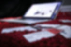 Laptop on red carpet with scattered bank cards. The screen shows a website. The scene suggests online shopping or processing.