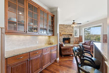 Kitchen view with windowed cabinets, island stools, and adjacent fireplace seating