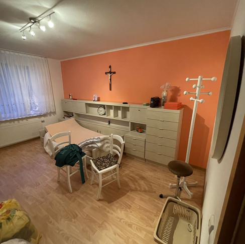 Schlafzimmer aus den 80er Jahren. Weißer Schrank am Kopfteil mit Schubfächern und Kruzifix an der Wand.