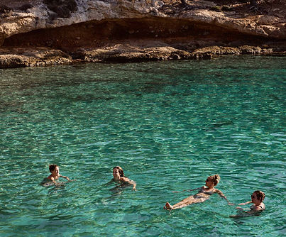 Group of people swimming in turquoise waters during a retreat excursion in Greece.