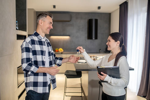 happy-man-taking-keys-from-realtor-woman-standing-indoors.jpg