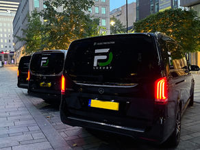 Black luxury minibuses for hire with "FD LUXURY" logos parked on a city street in Leeds UK