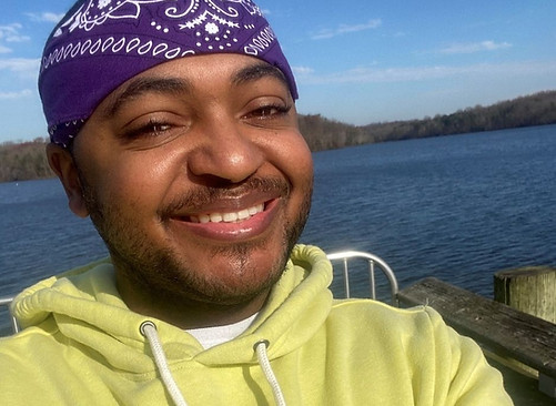 Man smiling outdoors near a waterfront
