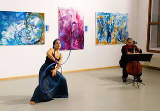 Aufnahme einer Hoopdane Performance bei einer Ausstellung, mit Bella Ressy als Hoopartist und Monica Mühleise am Cello
