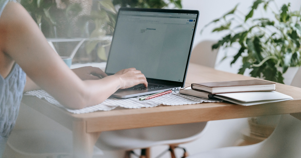 A person sitting at a table typing on a laptop.