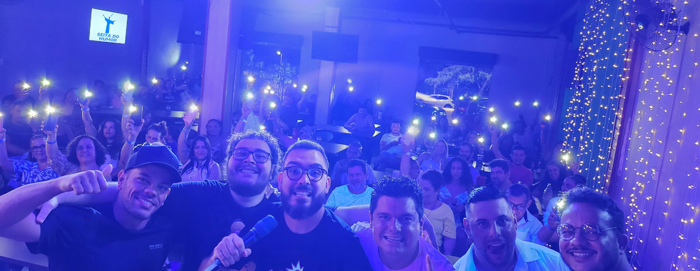 Comediantes na foto com a plateia ao fundo