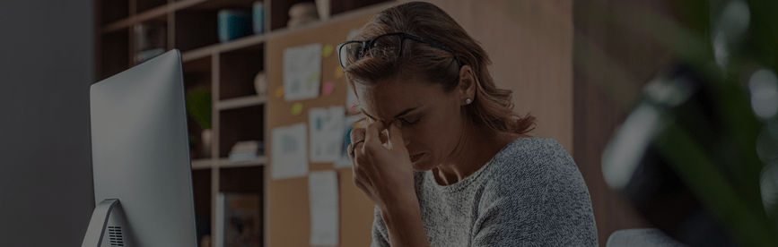 A woman with her hands on her face, stressed about meeting requirements