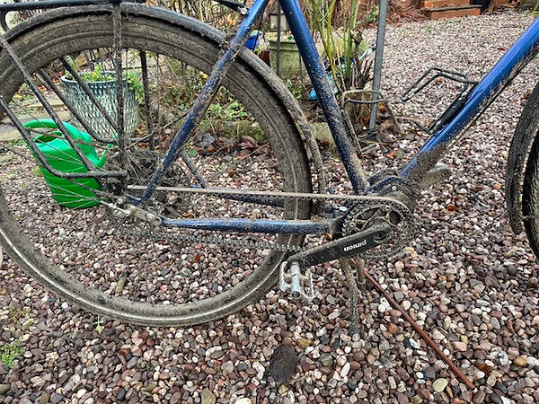 Biccledrive train and rear wheel and frame covered in mud.