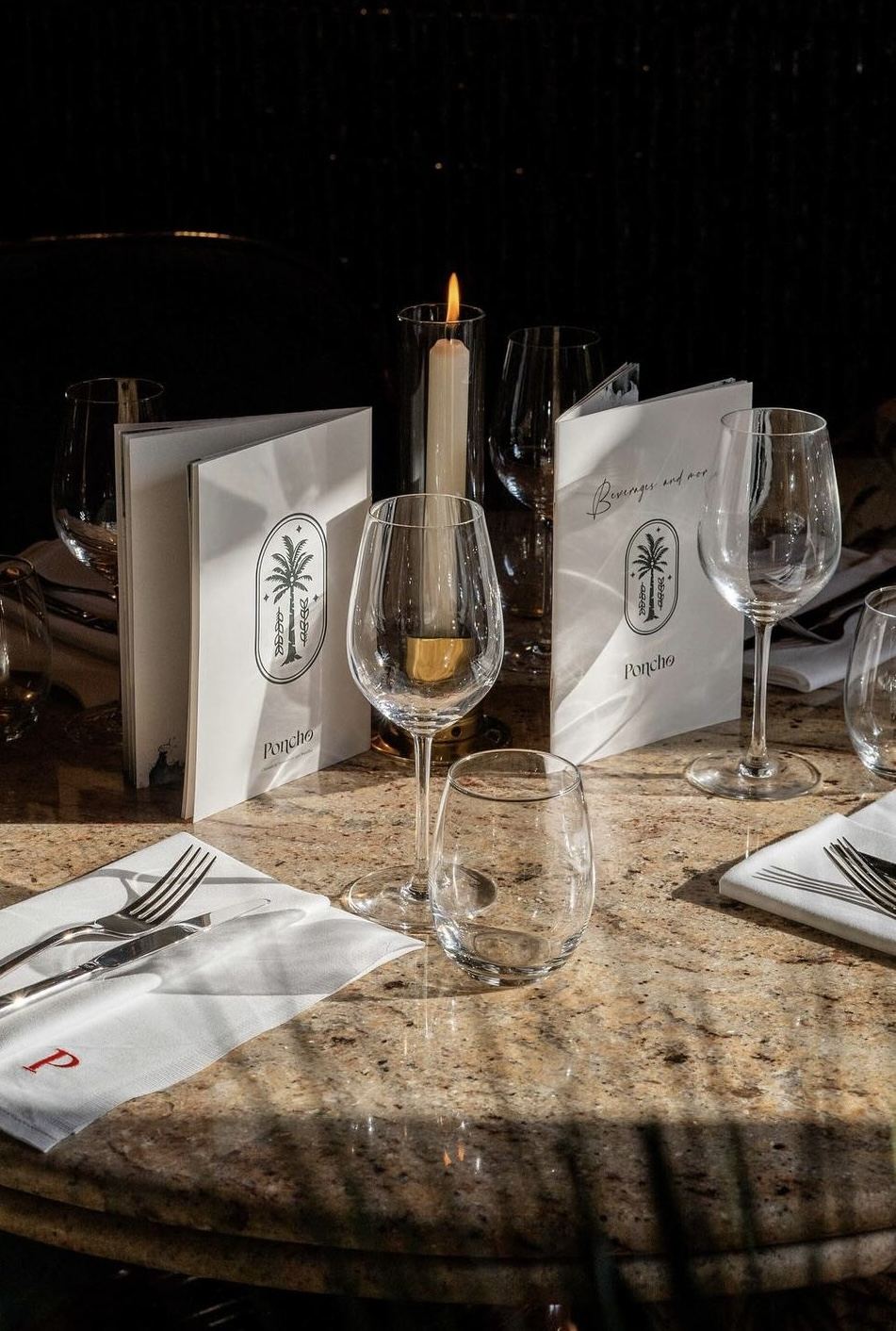 Les menus du Poncho sur une table en marbre, à la bougie