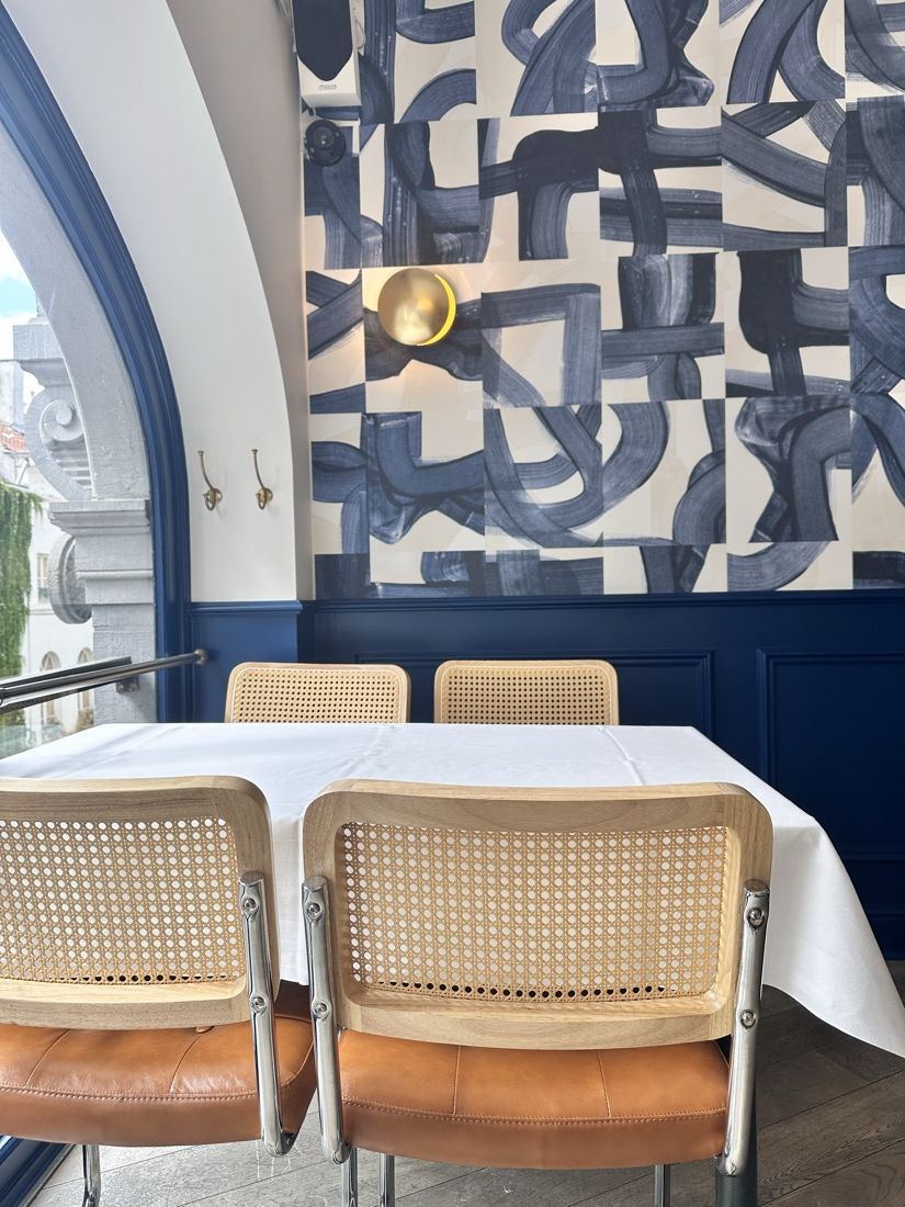 Banquette cognac et applique en laiton devant le papier peint