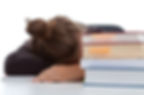 Student sleeping on the desk with a stack of books