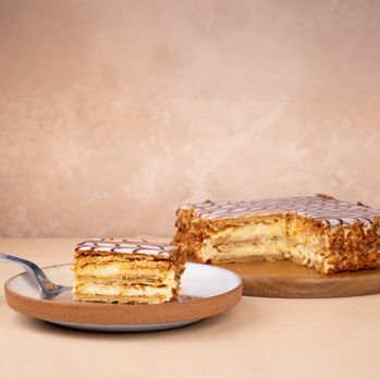 A slice of the Napoleon cake on a plate with the whole cake.
