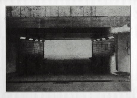 Abstract black and white image of a tunnel with squared ceiling and light.