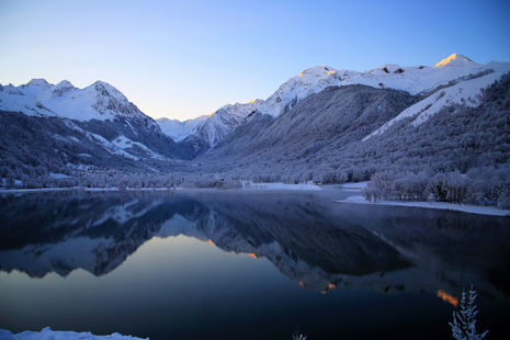 Snow-capped mountains reflect in the still lake; Nature Photography. Peaceful winter scenery.
