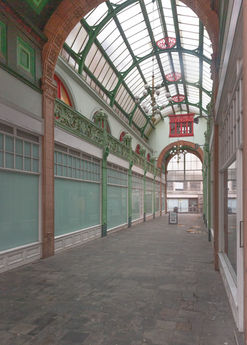 Interior view of a long hallway with glass windows and a curved glass roof. Architectural Photography