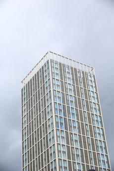 Tall skyscraper against a cloudy sky; Architectural Photography. Modern urban building structure.