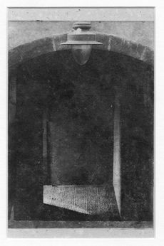 Dark doorway with light fixture above, leading into a shaded space