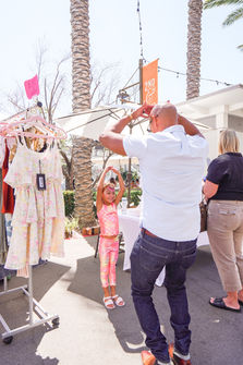 Father and daughter in front of dresses at the Dreamers Market.