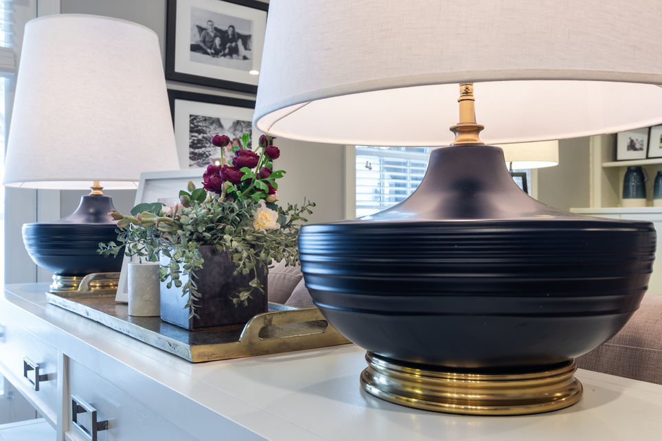 Blue and brass lamp on white console table with floral arrangement